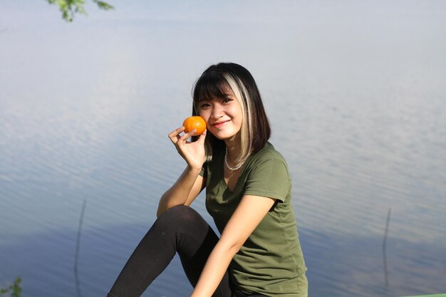 Asiatische Frau, die morgens zwei gelbe Orangen hält