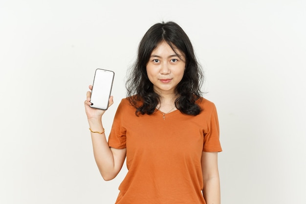 Asiatische Frau, die orangefarbenes T-Shirt trägt, das Smartphone hält und leeren Bildschirm zeigt oder präsentiert