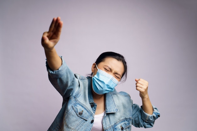 Asiatische Frau, die schützende Gesichtsmaske trägt, die drei Finger isoliert zeigt.