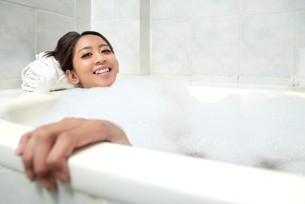 Asiatische Frau, die sich auf der Badewanne entspannt