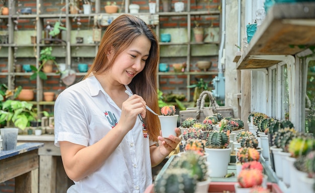 Asiatische Frau, die sich mit Kaktus im Garten entspannt. Home Gardening Lifestyle im Sommerurlaub.