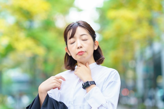 Asiatische Frau, die sich um Halsschmerzen kümmert