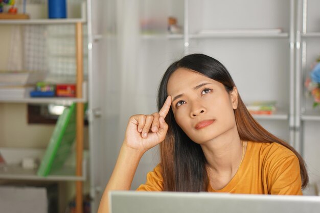 Asiatische Frau, die von zu Hause aus arbeitet, müde von Papierarbeit, die nicht pünktlich abgeschlossen wird