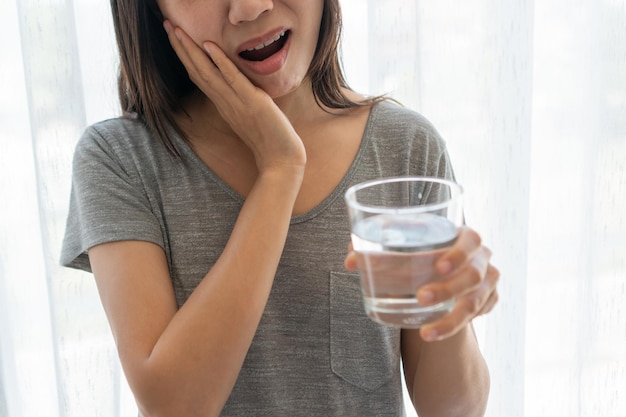 Asiatische Frau, die Zahnschmerzen verspürt Nahaufnahme eines traurigen Mädchens, das nach dem Trinkwasser unter Zahnschmerzen leidet Zahngesundheit und Zahnpflege Problemkonzept Kopieren Sie Platz