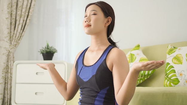 Asiatische Frau, die zu Hause mit voller Konzentration Yoga praktiziert