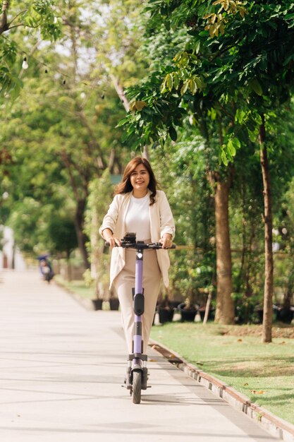 Asiatische Frau fährt auf einem elektrischen Roller im Park Lifestyle-Konzept