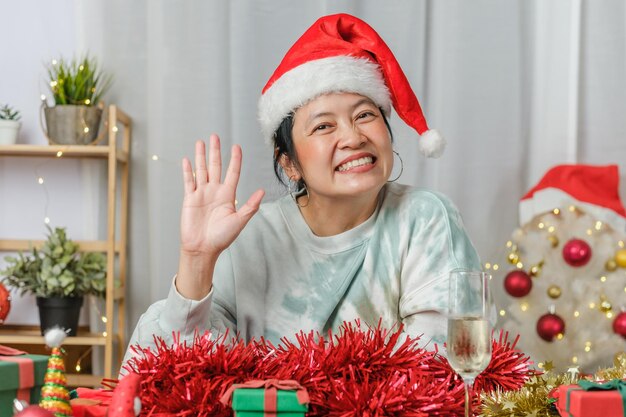 Asiatische Frau feiert Neujahr und Weihnachtsfeier mit Tablet-Videoanruf-Freunden zu Hause