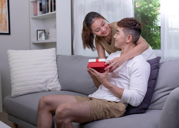 Asiatische Frau gratuliert ihrem Freund zum Geburtstag Das Paar überrascht den geliebten Mann mit einer Geschenkbox mit der anwesenden Familie, die Lebensereignisse feiert Paar-Lifestyle-Konzept