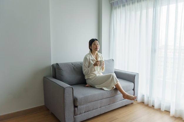 Asiatische Frau hält eine Tasse Kaffee in der Hand