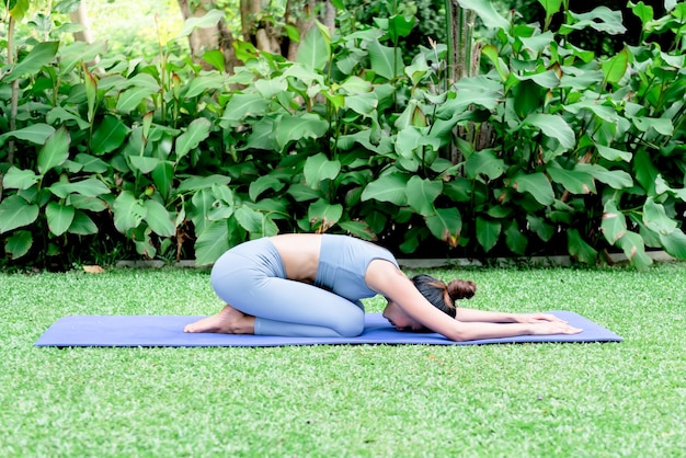 Asiatische Frau hat einen schönen Körper, der Yoga in einer eleganten Haltung im grünen Park spielt