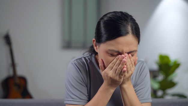 Asiatische Frau hatte Fieber, bekam Husten und fühlte sich auf dem Sofa im Wohnzimmer zu Hause unwohl