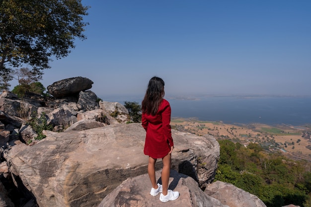 Asiatische Frau im Hintergrund mit Blick auf den Aussichtspunkt des Berggipfels mit nebligen Seedammblick und blauem Himmel am Aussichtspunkt Pha Muen, Khon Kaen, Thailand, Reiseattraktion