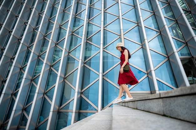 Asiatische Frau im roten Kleid am weiblichen Mädchen des modernen Gebäudes mit urbanem Stadtlebensstil