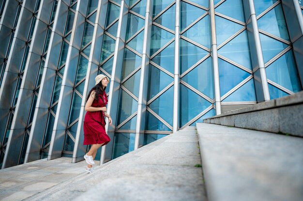 Asiatische Frau im roten Kleid im modernen Gebäude, weibliches Mädchen mit urbanem Stadtleben