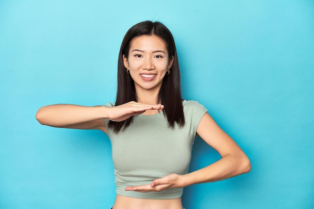 Asiatische Frau im sommergrünen Top-Studiohintergrund hält etwas mit beiden Händen