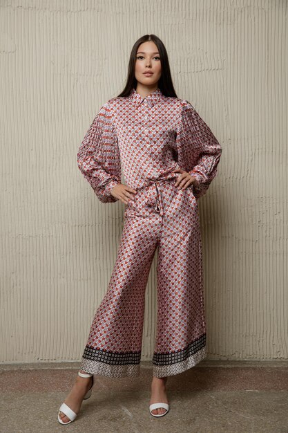 Foto asiatische frau in einem hübschen rosabraunen overall mit sandbeige-strukturierter wand