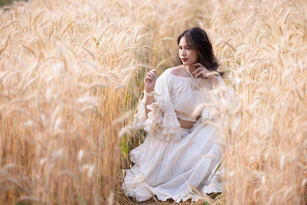 Asiatische Frau in einem Weizenfeld Portrait schöne Frau im Weizenfeld lächelnd Asiatische schöne Frauen im weißen Kleid zu Fuß goldene Gerstenfelder