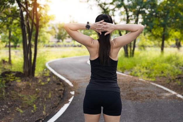 Asiatische Frau in Sportoutfits, die morgens vor dem Training im Freien im Park Stretching macht