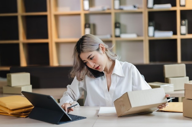 Asiatische Frau, KMU-Unternehmerin, Startup-E-Business-Inhaberin, nachdem sie die Bestellung von der Online-Shopping-Lieferung bis zum Kundenerfolgs-Shopping-Kleinunternehmen überprüft hat