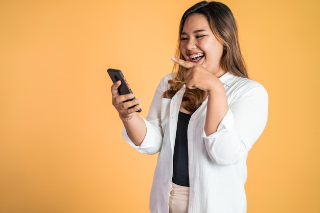 Asiatische Frau lacht, während sie auf ihren Smartphone-Bildschirm schaut