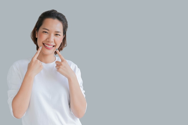 asiatische Frau lächelnd mit Zahnschienenhalter unsichtbar auf grauem Hintergrund isoliert