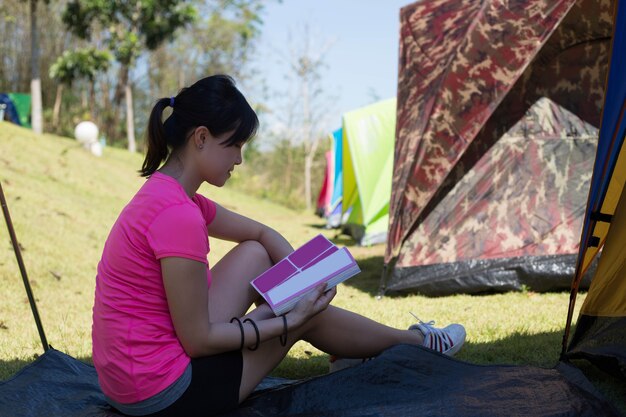 Asiatische Frau liest Buch im Freien.