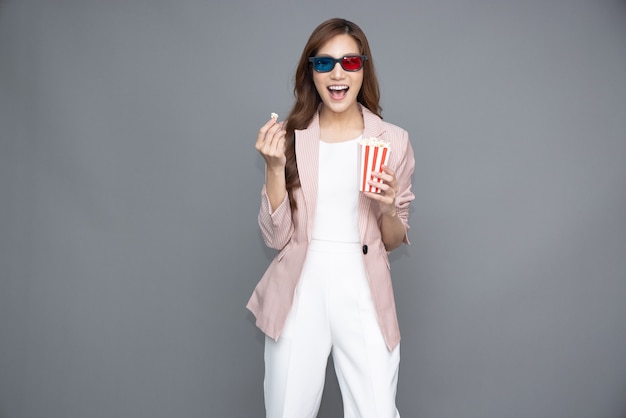 Asiatische Frau mit 3D-Brille, die Popcorn hält und isst