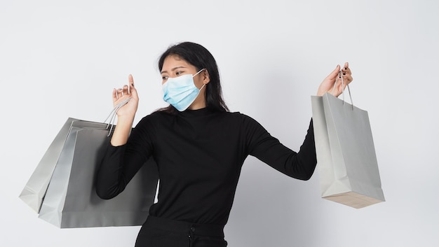 Asiatische Frau mit Gesichtsmaske hält Einkaufstasche
