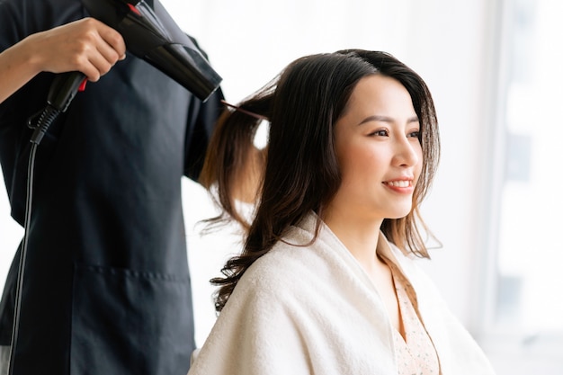 Asiatische Frau mit glücklichem Ausdruck, der Friseur am Salong tut