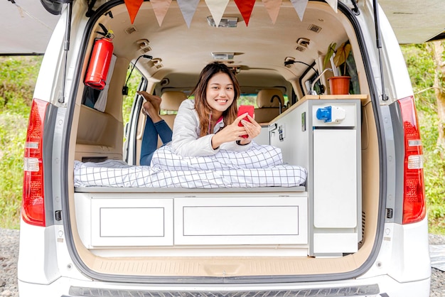 Asiatische Frau mit Handy im Wohnmobil