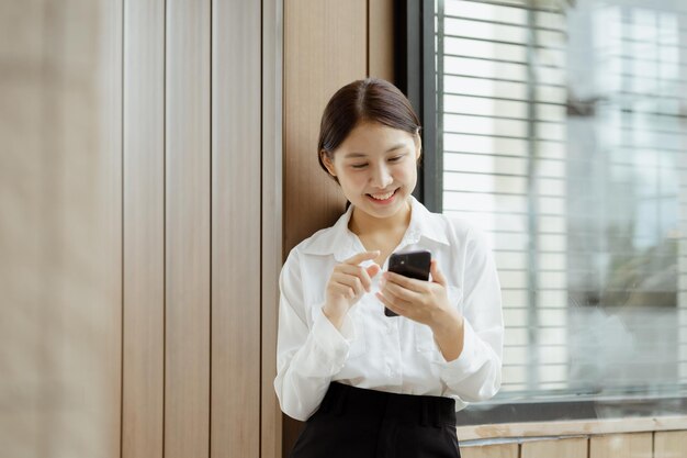 Asiatische Frau mit Handy surft sie im Internet und in sozialen Medien auf dem Smartphone und chattet mit Freunden über die App Das Konzept der Verwendung von Technologie in der Kommunikation und der Nutzung des Internets