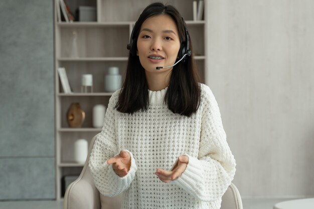 Asiatische Frau mit Headset im Gespräch mit Kamera-Videoanruf-Videokonferenz mit ihren Geschäftspartnern