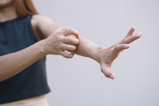 Asiatische Frau mit juckender Haut am Arm