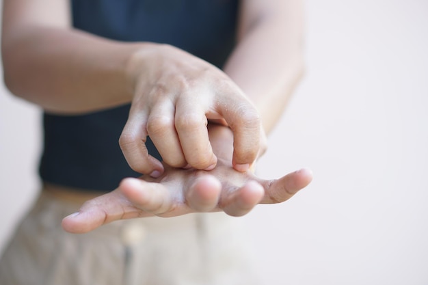 Asiatische Frau mit juckender Haut an der Hand