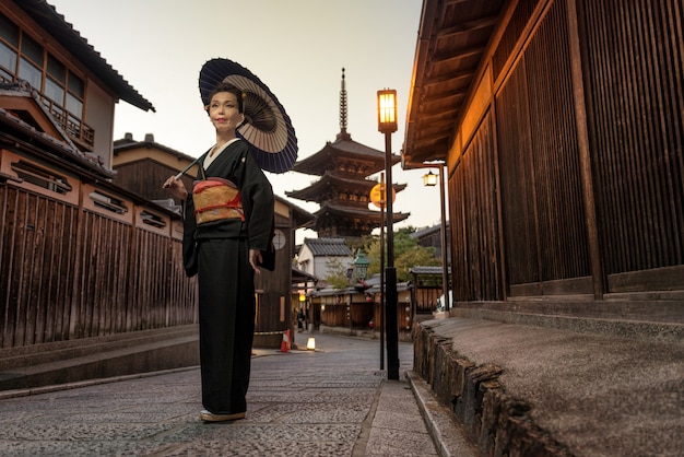 Asiatische Frau mit Kimono, die an Yasaka-Pagode in Kyoto geht