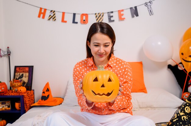 Asiatische Frau mit Kürbisgesicht für Halloween-Festival zu Hause. Schlafzimmerdekoration für Kinder- und Familienfeiern im Herbst und Herbst.