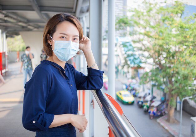 Asiatische Frau mit kurzen Haaren trägt eine medizinische Gesichtsmaske als neuen normalen Lebensstil.