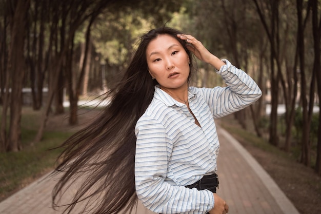 Asiatische Frau mit langen schwarzen Haaren, die im Stadtpark spazieren geht