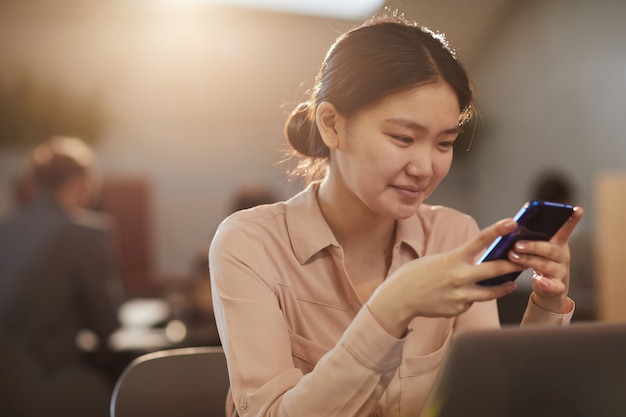 Asiatische Frau mit Smartphone im Cafe