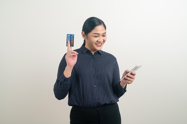 Asiatische Frau mit Smartphone mit der Hand, die Kreditkarte auf weißem Hintergrund hält