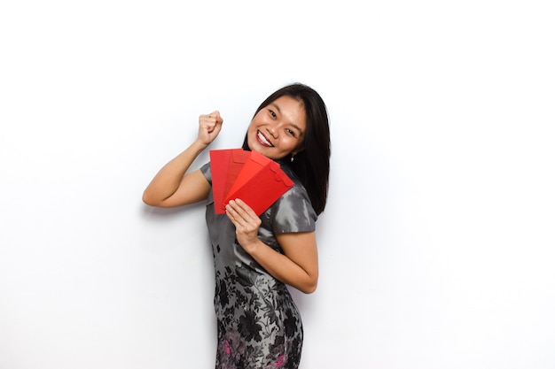 Asiatische frau mit traditionellem cheongsam zeigt und hält roten umschlag angpau