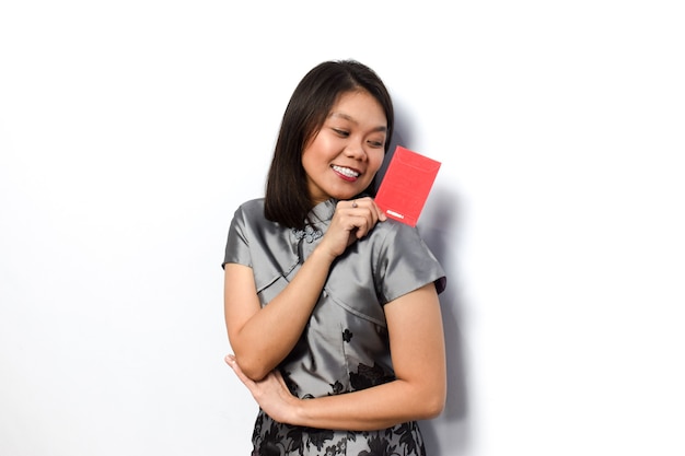 Asiatische Frau mit traditionellem Cheongsam zeigt und hält roten Umschlag Angpau