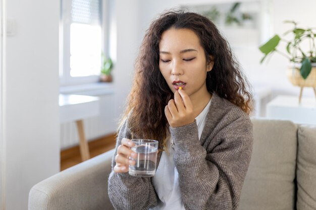 Asiatische Frau nimmt Medikamente mit einem Glas Wasser Tägliche Norm von Vitaminen wirksame Medikamente