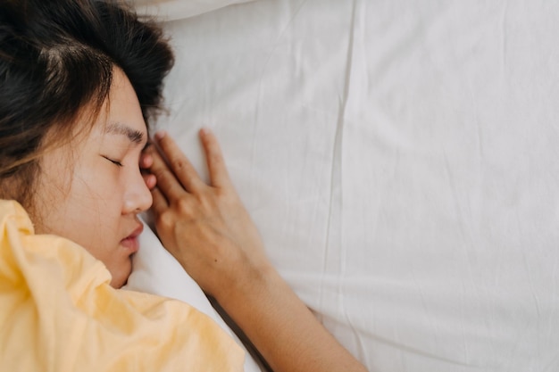 Asiatische Frau schläft tief, weil sie müde und krank ist