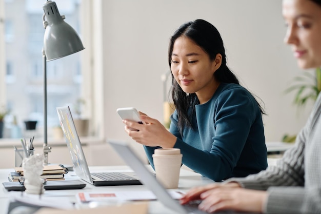 Asiatische Frau scrollt eine Webseite auf ihrem Smartphone