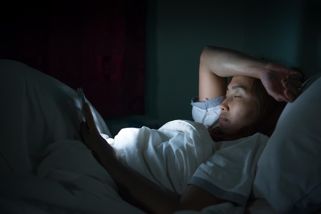 Asiatische Frau spielt nachts Smartphone im BettThailänder