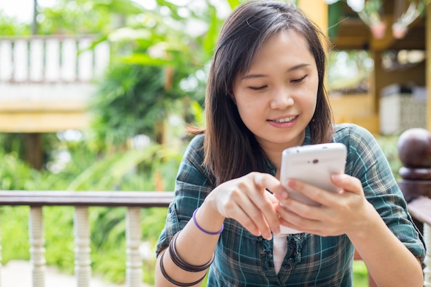 Asiatische Frau spielt zu Hause Smartphone.