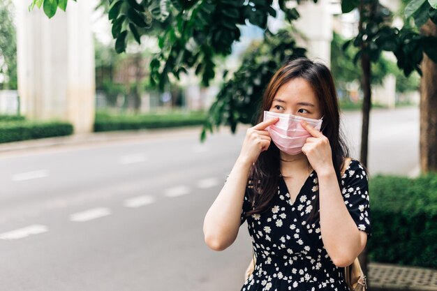 Asiatische Frau trägt Gesichtsmaske zum Schutz vor dem Ausbruch des Coronavirus COVID19 in der Stadt
