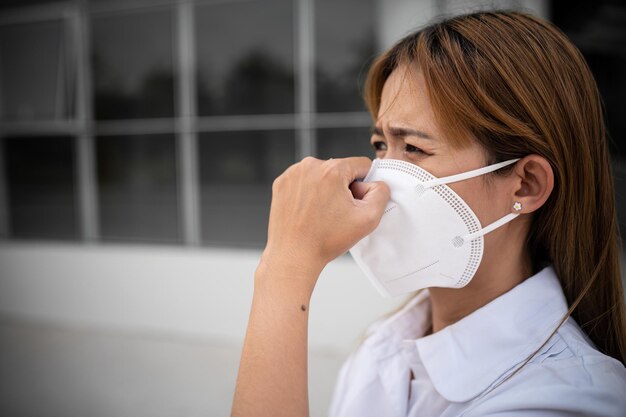 Foto asiatische frau trägt n95-maske zum schutz vor staub pm 25 ökologie-konzept allergie kopfschmerzen luftgefahr in der stadt