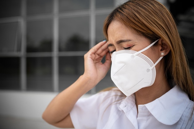 Foto asiatische frau trägt n95-maske zum schutz vor staub pm 25 ökologie-konzept allergie kopfschmerzen luftgefahr in der stadt